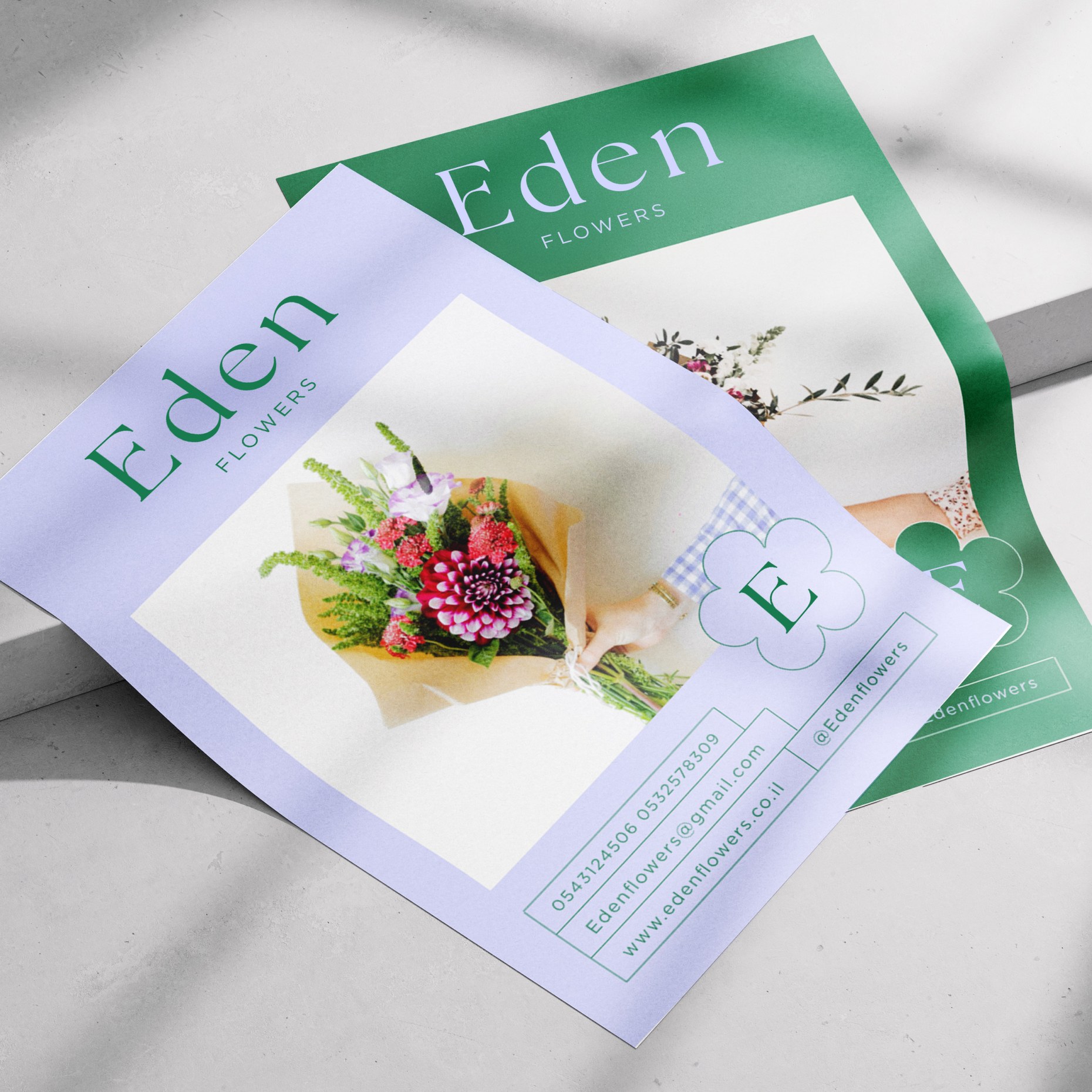 Lilac and green Eden flyers overlapping on a concrete surface in raking light